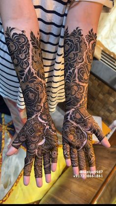 two hands with henna tattoos on them, one is showing off the intricate design