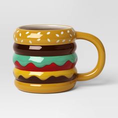 a yellow coffee mug with hamburgers painted on the outside and inside, sitting in front of a white background