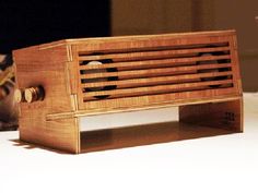 a wooden radio sitting on top of a white table next to a brown and black cat