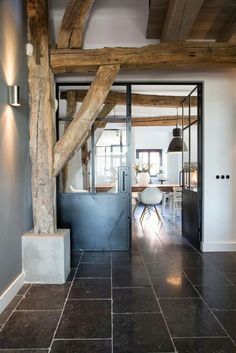 an open door leading to a kitchen and living room with wood beams on the ceiling