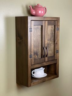 a wooden cabinet with a teapot on top and a white cup in the corner