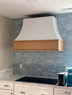 a stove top oven sitting inside of a kitchen next to white cupboards and drawers