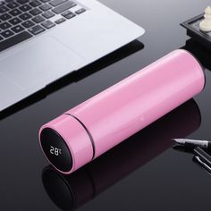 a pink battery sitting on top of a desk next to a laptop computer and pen