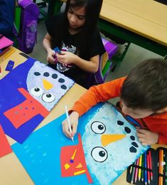 two children are making paper snowmen with crayons