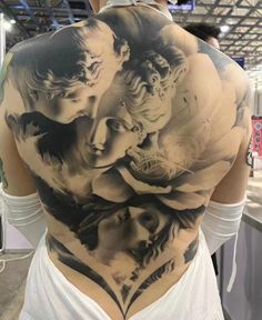 the back of a woman's body is covered in tattoos and features an image of two