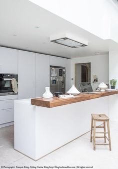 a modern kitchen with white cabinets and counter tops, along with an island in the middle