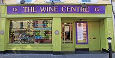 the front of a wine shop with purple and green signage