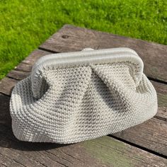 a white purse sitting on top of a wooden table next to a grass covered field