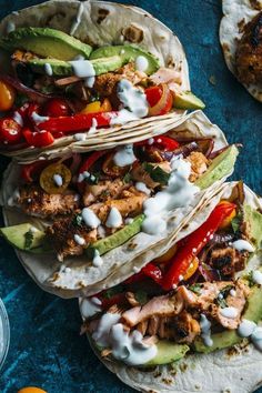 three chicken fajitas with tomatoes, avocado and sour cream on top