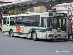 a green bus is parked on the side of the road in front of an overpass