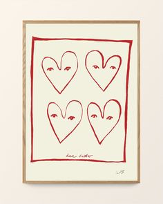 three hearts with faces drawn on them in red ink, framed in white paper and wood frame