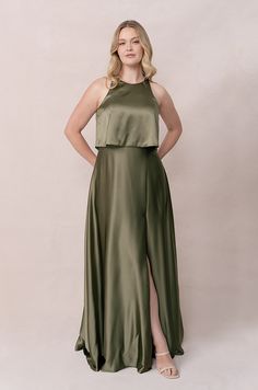 a woman in a long green dress standing with her hands on her hips