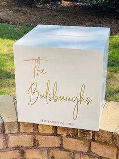 a white box sitting on top of a brick wall next to a grass covered field