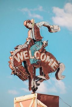 a sign that says welcome on top of a building with a cowboy riding a horse