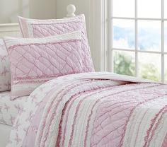 a bed with pink and white bedspread in a room next to a window