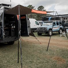 an rv parked in the grass with its doors open and other vehicles behind it at a camp site