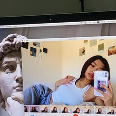 a woman taking a selfie in front of a computer screen with an image of a statue on it