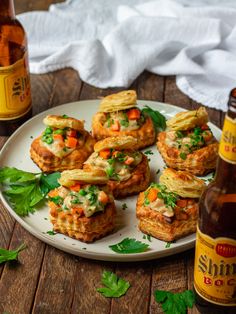 some food is sitting on a white plate next to a beer bottle and napkins