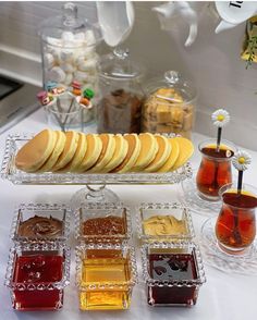 there are many different types of jellys on the table with cups and saucers