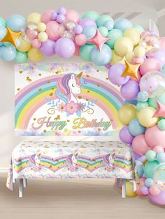 a unicorn themed birthday party with balloons, streamers and a rainbow bench for the kids to sit on