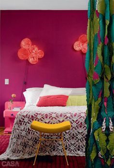 a bedroom with pink and green walls, white bedspread and red pillows on the bed