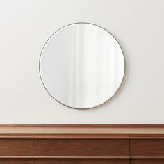 a round mirror sitting on top of a wooden dresser