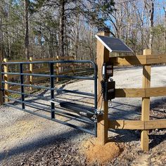 a fence with a solar panel attached to it in the middle of a wooded area