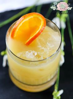 an orange slice sitting on top of a drink in a glass with ice and garnish