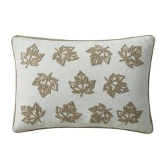 a white and gold pillow with leaves on the front, along with an embroidered back