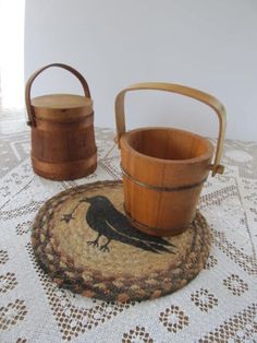 two wooden buckets sitting on top of a table next to a basket with a bird painted on it