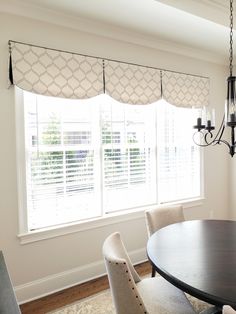 a dining room table with four chairs and a chandelier hanging from the ceiling