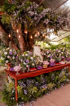 a table topped with lots of flowers under a tree