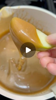 a spoon full of caramel sauce being held up by someone's hand with an apple in it