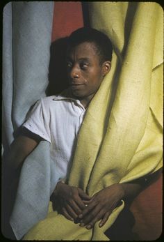 a man hiding behind a yellow curtain with his head between two pieces of cloths