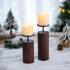 two candles sitting on top of each other in front of a christmas tree and decorations