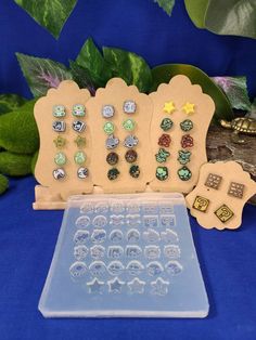 an assortment of earrings are displayed on a blue tablecloth with green leaves in the background