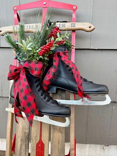 a pair of ice skates sitting on top of a wooden sled filled with greenery