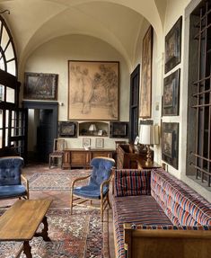 a living room filled with furniture and paintings on the wall above it's windows