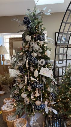 a christmas tree decorated with blue and white ribbons, ornaments and snowflakes