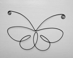 a metal butterfly with swirls on it's wings, sitting against a white wall