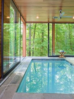 an indoor swimming pool in the middle of a house with glass walls and sliding doors