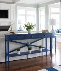 a blue console table with two potted plants sitting on it's top shelf