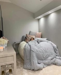 a woman laying on top of a bed under a blanket