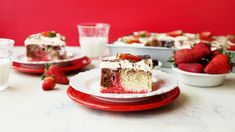 a piece of cake on a plate with strawberries and milk in front of it