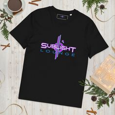 a black t - shirt with the words sunlight lounge on it next to a cup of coffee