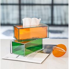 an orange and green tissue dispenser sitting on top of a white table