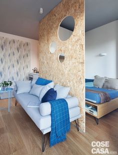 a blue couch sitting in front of a wooden wall next to a white chair and table