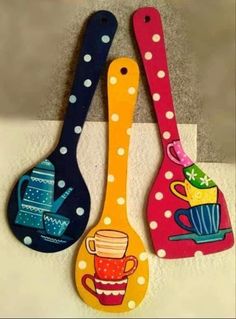 three colorful spoons with designs on them sitting next to each other in front of a wall