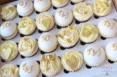 cupcakes with white frosting and gold decorations in a box