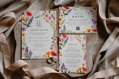 the wedding stationery is laid out on top of the fabric